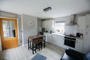 a kitchen with white cabinets and a table with chairs at Terry Joe Cottages in Newry