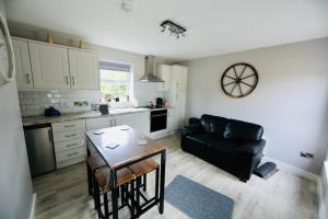 a kitchen with a table and a black leather couch at Terry Joe Cottages in Newry +20 photos