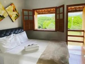 um quarto com uma grande cama branca e uma janela em Pousada Engenho Velho em Serra do Cipo