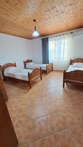 a room with three beds and a wooden ceiling at Appartamento vicino al centro storico in Shkodër