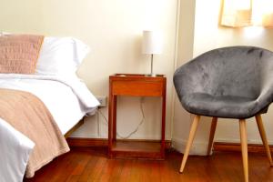 a bedroom with a chair next to a bed at Maison verte - Guest House in Arequipa