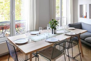 stół jadalny z krzesłami i duże okno w obiekcie Wonderful flat in Paris - Welkeys w Paryżu