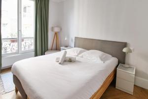 sypialnia z białym łóżkiem z pluszowym misiem w obiekcie Wonderful flat in Paris - Welkeys w Paryżu