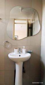 La salle de bains est pourvue d'un lavabo blanc et d'un miroir. dans l'établissement MINI DEPARTAMENTO independiente, privado y cómodo, à Arequipa