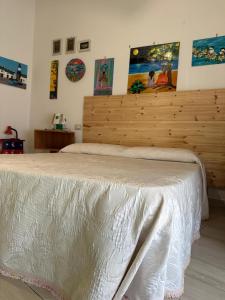 Schlafzimmer mit einem weißen Bett mit einem Kopfteil aus Holz in der Unterkunft La casa di Beatrice in Catanzaro Lido