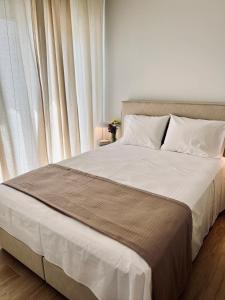 a bed with white sheets and pillows next to a window at Jack, 2 people, renovated stylish apartment in Athens