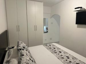 Un dormitorio blanco con una cama y un armario. en Bela Cintra Flat Service, en São Paulo