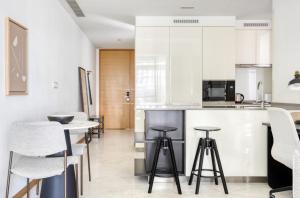 a kitchen with white cabinets and bar stools at The Modern Loft 1BR in Singapore! in Singapore