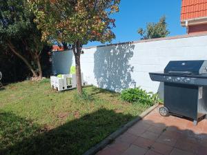 a barbecue grill in a yard next to a fence at SANTANDER-LIENCRES VILLA PERAL in Liencres