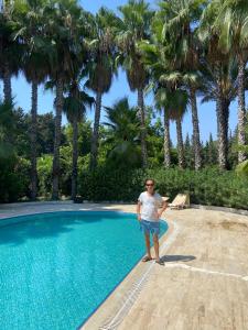 a man standing next to a swimming pool with palm trees at Paradise Manavgat in Manavgat