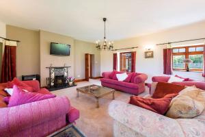 a living room with pink couches and a tv at Super Spacious Country house pet/party friendly. in Newquay