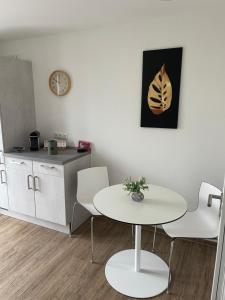 une table et des chaises blanches dans une cuisine avec une horloge dans l'établissement AM Fleurystr, ALL NEW, komfortabel, ZENTRAL in Amberg!!!, à Amberg
