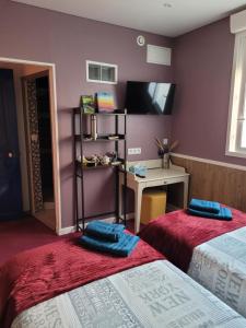 Zimmer mit 2 Betten, einem Schreibtisch und einem TV in der Unterkunft Le Relais De L'Aube in Villers-Bretonneux