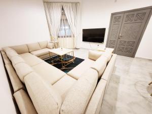 a living room with a large couch and a table at Moods Holiday Homes in Al Ain