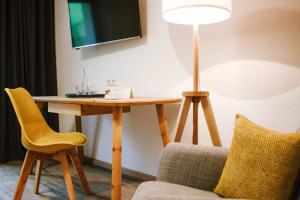 een kamer met een tafel, een gele stoel en een lamp bij Hotel Schönberg B&B in Rio Bianco