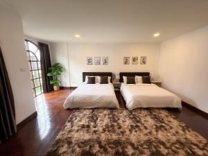 two beds in a room with a rug at Thonglor 25 Classic Home 5BR/7Beds/14PPL in Ban Na Song