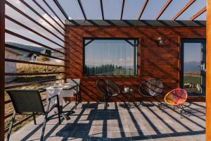 ein Haus mit 3 Stühlen und einem Tisch auf einer Terrasse in der Unterkunft Zen Nest Tiny House in Şirnea