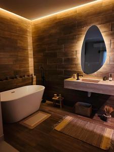 Un baño con bañera, lavabo y espejo. en Luxury Mali Lofts, en Cancún