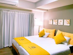大阪的住宿－Shinkou House UE，配有黄色枕头的酒店客房的两张床