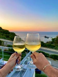 two people holding glasses of white wine on a balcony at Zabb&agrave;ra B&B in Terrasini