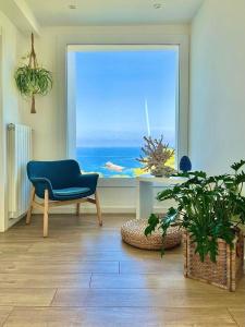 a living room with a blue chair and a large window at Zabbàra B&B in Terrasini