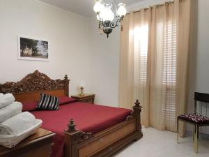 a bedroom with a red bed and a chandelier at Selinunte Street House in Castelvetrano Selinunte