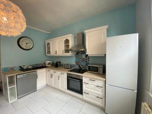 a kitchen with white cabinets and a clock on the wall at La Clé de Julian in Amiens