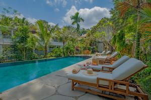 an infinity pool with lounge chairs and a pool house at The Kanjeng resort Ubud in Ubud