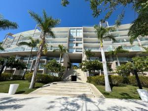 a large building with palm trees in front of it at Departamento Pacific Luxury Punta Mita, Beachfront in Higuera Blanca