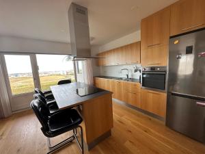 uma cozinha com armários de madeira e um frigorífico de aço inoxidável em Apartment in Austurkór- Birta Rentals em Reykjavík