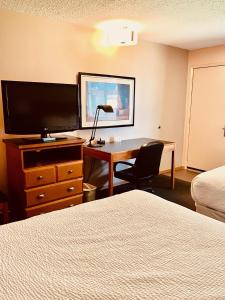 um quarto de hotel com uma secretária, uma televisão e uma cama em Royal Hotel Lloydminster em Lloydminster