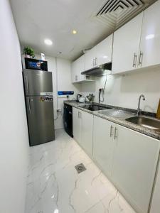 uma cozinha com armários brancos e um frigorífico de aço inoxidável em DSV Property em Abu Dhabi