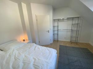 ein Schlafzimmer mit einem weißen Bett und einem Schrank in der Unterkunft Ruhiges DG - 6 P. - urban - ÖPNV in Köln