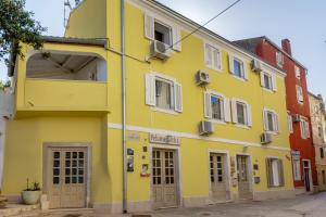 een geel gebouw aan de straatkant bij Apartments Mandarina in Mali Lošinj
