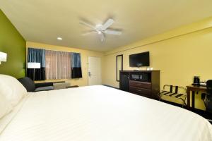 1 dormitorio con 1 cama blanca grande y TV en Quality Inn - Needles, en Needles