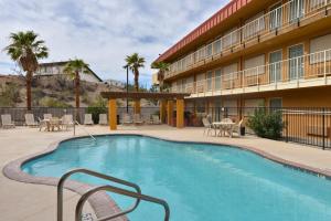 a pool in front of a hotel with tables and chairs at Quality Inn - Needles in Needles