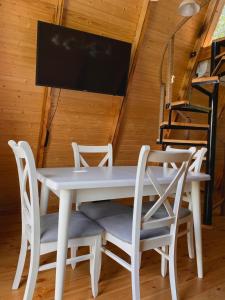 mesa de comedor blanca con sillas y TV de pantalla plana en HillSide Cottage, en K'eda