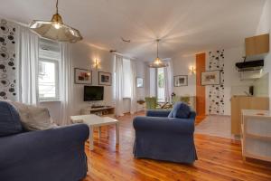 a living room with two blue chairs and a television at Apartments Mandarina in Mali Lošinj