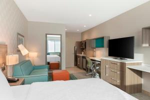a hotel room with a bed and a desk with a television at Home2 Suites By Hilton Redlands in Redlands