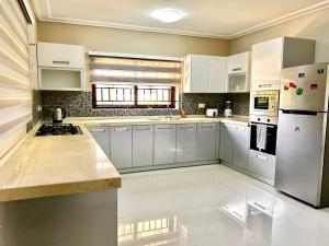 a large kitchen with white cabinets and white appliances at Aspen Luxury Villa in Accra