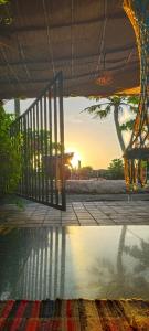 une porte ouverte menant à une piscine avec le coucher de soleil en arrière-plan dans l'établissement Peace and love stay, à Alappuzha