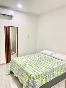 a bedroom with a bed with a green and white comforter at Bonito Apartamento Monteria in Montería