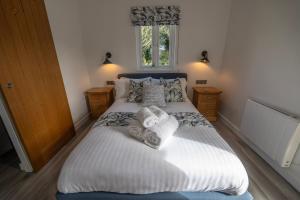 una camera da letto con un grande letto con lenzuola e cuscini bianchi di Olverstone Lodge, a beautiful Cornish lodge with wood burner & garden a St Austell