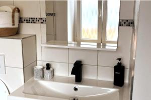 ein weißes Bad mit einem Waschbecken und einem Fenster in der Unterkunft Le 31 - Mulhouse Pfastatt in Pfastatt