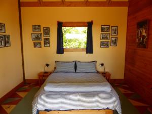 um quarto com uma cama com uma janela e quadros na parede em The Old Slaughterhouse Traveller's Lodge em Hector