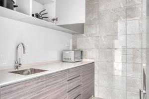 a kitchen with a sink and a microwave at The Elite Enclave 2Bedroom Apartment in Singapore! in Singapore