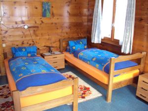 two beds in a bedroom with wooden walls at Heiderösli 1st Floor and Attic Apartment in Grächen