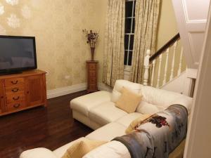 a living room with a white couch and a television at The Apartment Benone in Castlerock