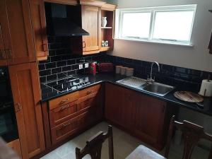 a kitchen with wooden cabinets and a sink and a window at The Apartment Benone in Castlerock