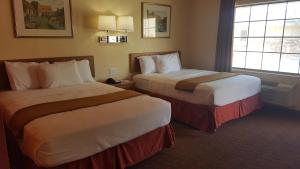 a hotel room with two beds and a window at Stadium Motel - Lubbock Medical Center in Lubbock +1 photo